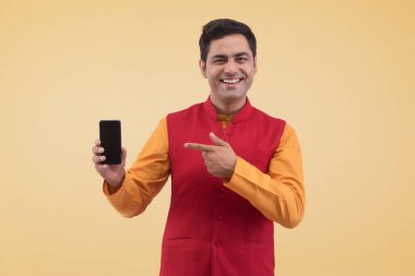 Genç adam cep telefonunu tutuyor ve ona doğrultuyor.