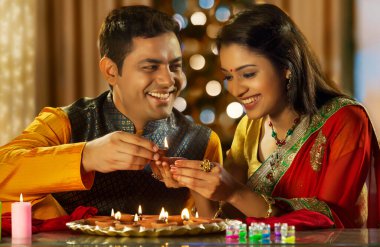 Genç bir çift Diwali vesilesiyle evi diya ile dekore ediyor.