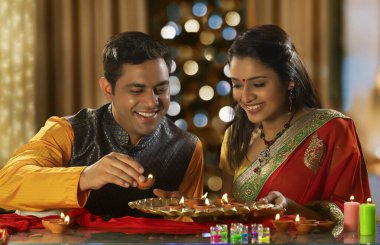 Genç bir çift Diwali vesilesiyle evi diya ile dekore ediyor.