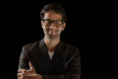 Kameraya bakan iş adamı siyah arka planda gözlük takıyor.