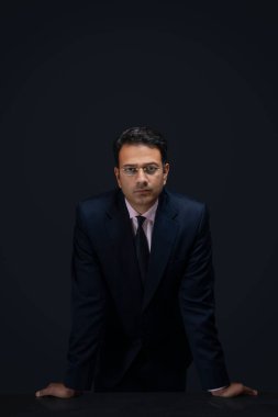 Gözlüklü bir iş adamının portresi. Elleri masanın üzerinde duruyor.