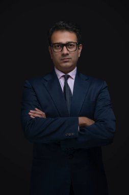 Kollarını kavuşturmuş, gözlüklü bir iş adamının portresi.