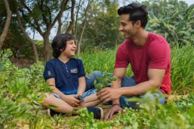 Babası elinde yapraklı sebzeler tutarken, mutlu çocuk bahçeden yapraklı sebzeler kesiyor..