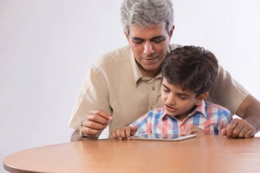 Dedesi ve birlikte dijital tablet kullanarak oturan torunu