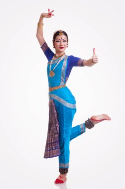 Beyaz arka planda Bharatanatyam yapan kendinden emin genç bir kadının tam boy portresi