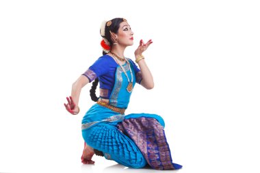Beyaz arkaplana karşı Bharatanatyam 'ı seslendiren dansçının yan görünümü