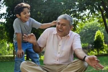 Grandson tickling grandfather in ear clipart