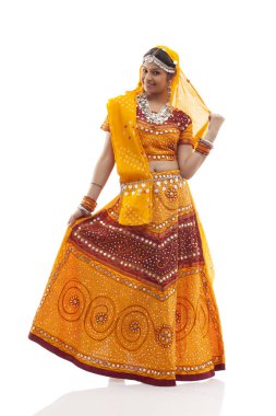 Chaniya choli giyen uzun boylu bir kadın beyaz arka planda izole edilmiş.