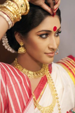 Bengali woman putting sindoor on her forehead clipart