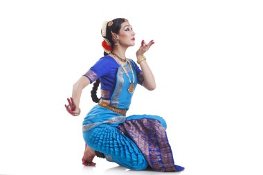 Beyaz arkaplana karşı Bharatanatyam 'ı seslendiren dansçının yan görünümü