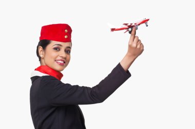 Beyaz arka planda izole edilmiş oyuncak uçak tutan bir hostesin portresi.