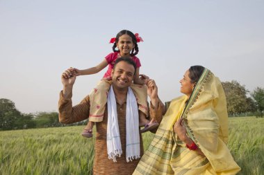 Tarladaki neşeli kırsal bir ailenin portresi.