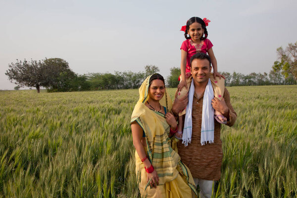 Портрет сельской индийской семьи с отцом, несущим дочь на плечах