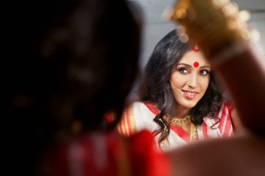 Bengali woman looking at herself in the mirror clipart