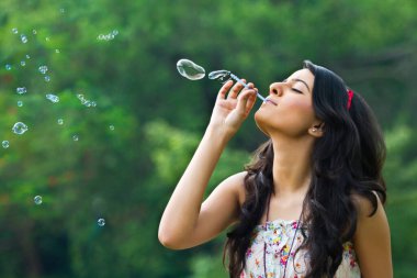 genç kadın bir parkta kabarcıklar üfleme