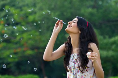 genç kadın bir parkta kabarcıklar üfleme