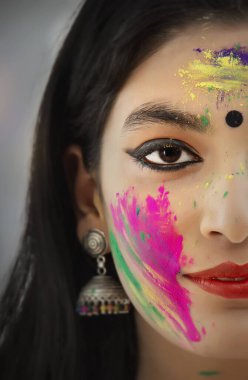 CLOSE SHOT OF A YOUNG WOMAN WITH GULAL ON HER FACE clipart