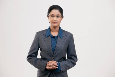 Gri arka planda izole edilmiş takım elbiseli genç iş kadını portresi