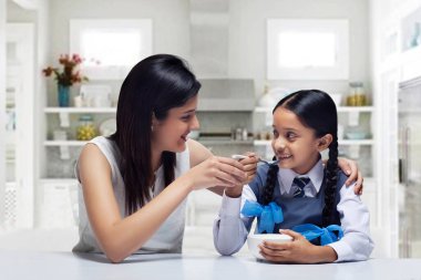 Anne kızını evde kahvaltıyla besliyor.