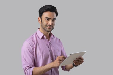 Resmi giysiler içinde elinde dijital tabletle kameraya bakan bir çalışan..