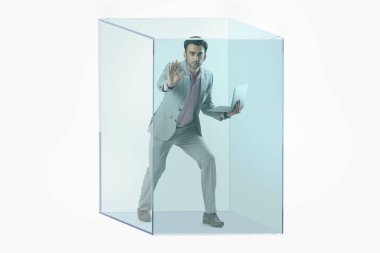 Resmi takım elbiseli bir adamın portresi. Elinde şeffaf bir küpün içine sıkışmış bir laptop var..