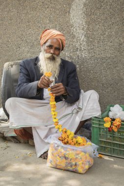 Pazarda çiçek çelengi satan bir adamın portresi.