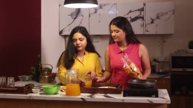 İki kadın dedikodu yaparken yemek pişiriyor ve abur cuburlarının tadını çıkarıyor.
