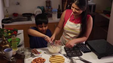 Oğlum çırpıcıyla hamuru karıştırıyor ve tutarlılığı kontrol ediyor.