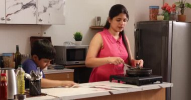 Anne yemeği ve oğlu mutfağı temizliyor.