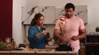 Mutfaktaki tavada yemek pişiren çiftler.