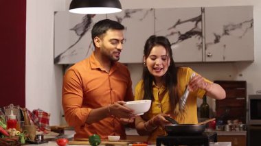 Karı koca mutfakta birlikte yemek pişiriyorlar.