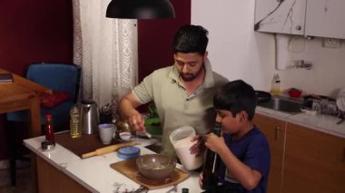 Baba ve oğul mutfakta yemek pişiriyor.