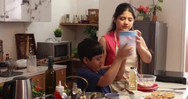 Anne ve oğlu mutfakta birlikte yemek pişiriyorlar.