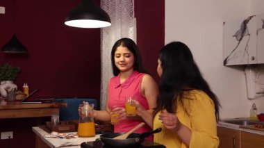 Mutfakta dedikodu yaparken içkinin tadını çıkaran iki kadın.