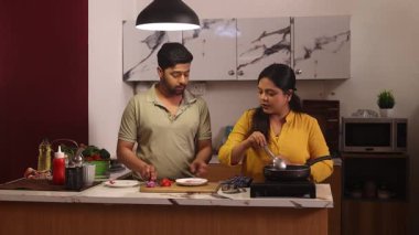 Çiftler mutfakta birlikte yemek pişiriyor.