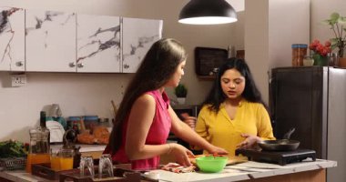 İki kadın dedikodu yaparken yemek pişiriyor ve abur cuburlarının tadını çıkarıyor.