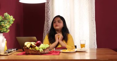 Dizüstü bilgisayarla çalışırken turuncu yemekten hoşlanan bir kadın.