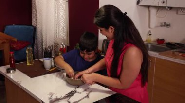 Anne ve oğul hamur hazırlıyor ve birbirlerine sataşıyorlar.