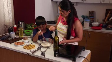 Oğlum çırpıcıyla hamuru karıştırıyor ve annesi yardım ediyor.