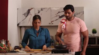 Kadın şapkayı yuvarlarken, adam tavada şapkayı pişiriyor.