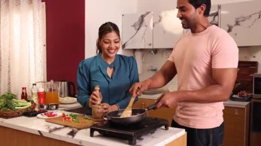 Bir çift yemek pişiriyor ve mutfakta birbirleriyle konuşuyorlar.