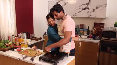Karı koca mutfakta birlikte yemek pişiriyorlar.