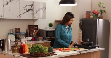 Mutfakta yemek yapan evli bir kadın.