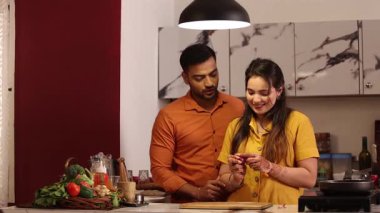 Mutlu çiftler evde mutfakta akşam yemeği için yeşil sebze salatası hazırlıyor ve pişiriyor.