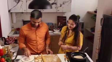 Yemek pişiren mutlu ve sağlıklı bir çift evdeki mutfaklarında birlikte yemek hazırlıyor. Heyecanlı, kaygısız ve neşeli aşıklar yemek yaparken gülümsüyor ve gülüyorlar.