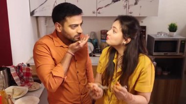 Kocası mutfak masasını mutfak örtüsüyle silerken karısı mutfakta ona yardım ediyordu.