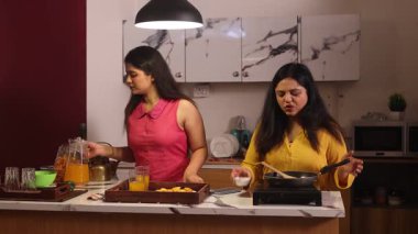 İki kadın birlikte temizlik ve yemek yapıyor.