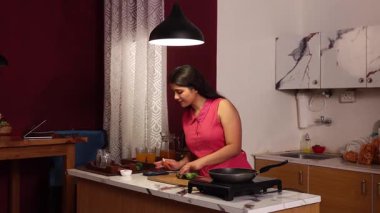 Müziğin tadını çıkarırken yemek yapan bir kadın.