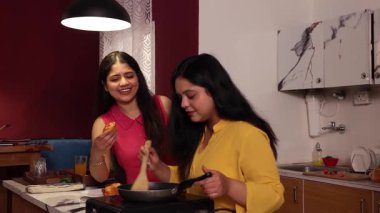 İki kadın birlikte kek pişiriyor ve kek yiyor.