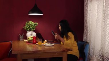 Dizüstü bilgisayarla çalışırken turuncu yemekten hoşlanan bir kadın.